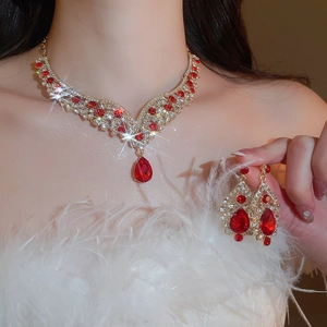 Elegant red teardrop gemstone necklace and earrings set worn by a model with feathers
