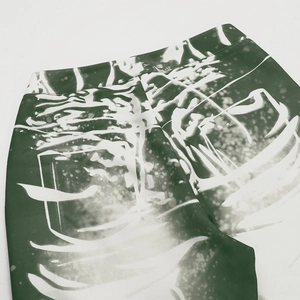 Close-up of dark green abstract print on twill trousers showing fabric texture