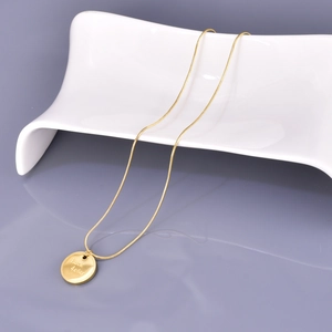 Gold stainless steel necklace with round Luck 4ever engraved coin pendant on white stand