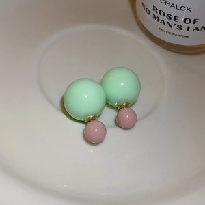 Macro shot of mint green and dusty pink double pearl earrings with gold metallic finish