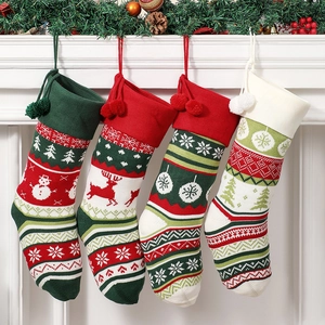 Set of four knitted Christmas stockings with snowman and reindeer hanging on fireplace