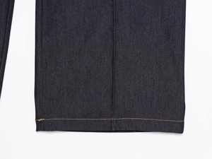 Gros plan sur l'ourlet du jean denim bleu foncé avec coutures contrastées de qualité