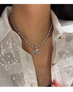 Detail of silver beaded necklace featuring a crystal rocking horse pendant on a model