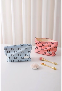 Close-up of pink and blue cotton makeup bags with bow patterns and zipper details