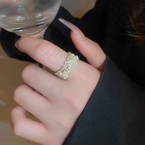 Detail of gold plated ring with pearls and small diamonds worn by a model holding glass