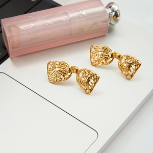 Detail view of gold bow earrings featuring an intricate hollow lava texture pattern
