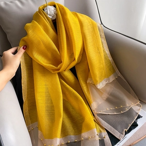 Detail of yellow silk shawl featuring gold beads, mesh trim and camellia flower accessory