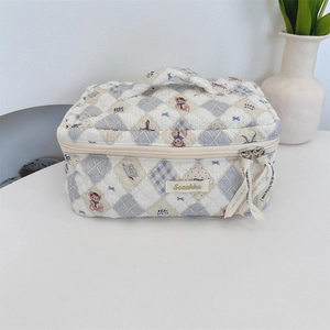 Quilted makeup bag detail with bear patterns, plaid design, and ribbon zipper pull