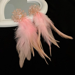 Macro detail of luxury pink feather earrings with crystal clusters on vintage heart prop