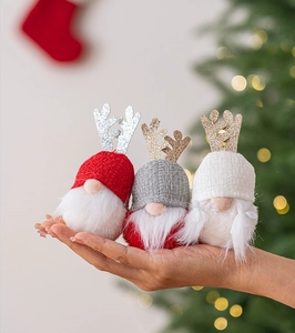 Close-up of three plush Christmas gnomes with sequined antlers held in palm for scale
