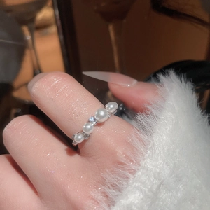 Close-up of elegant silver pearl ring with five white pearls worn on a finger