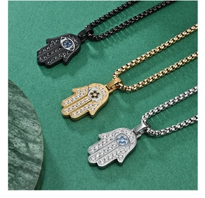 Detailed view of three Hamsa hand pendants in black, gold and silver with crystal pavé