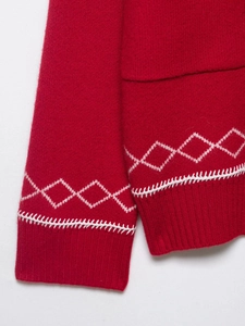 Dettaglio maglione rosso a maglia con ricamo a rombi e cuciture a contrasto