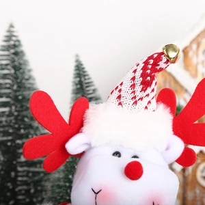 Close-up of plush Christmas reindeer ornament with red knit hat and gold bell detail