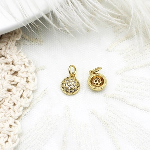 Macro view of gold micro-pave cubic zirconia charms with hollow back on lace and feathers