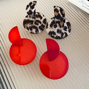 Detail view of leopard print and red resin geometric drop earrings on textured glass