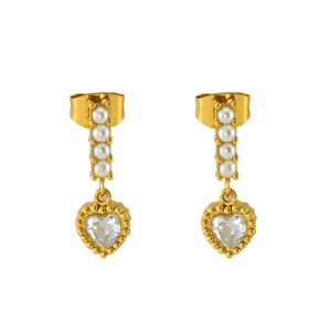 Detail of vintage heart-shaped zircon earrings with vertical pearls on gold metal