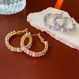 Detail of square zircon hoop earrings in gold and silver finish on textured stone