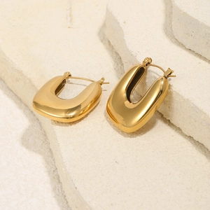 Polished 18K gold plated U-shaped hoop earrings on minimalist white stone display