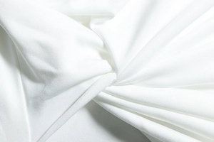 Detaillierte Makroansicht der weißen Strickstofftextur und Drapierung am Kleid