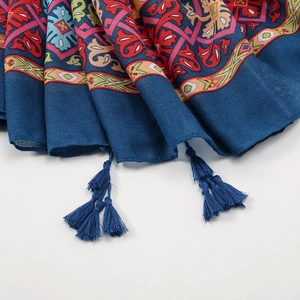 Detail of ethnic blue cotton linen scarf featuring vibrant patterns and tassel fringe