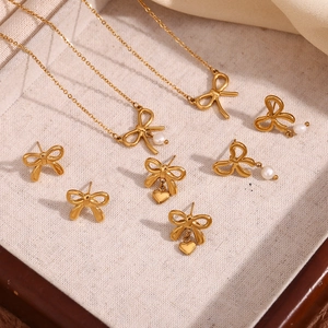 Detail of 18K gold bow jewelry set with freshwater pearls and heart pendants in a box