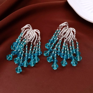 Close-up of vintage style silver tassel earrings with vibrant blue crystal beads
