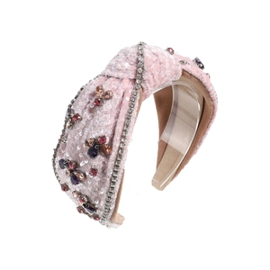 Pink velvet knotted headband with colorful rhinestones and sequins on white background