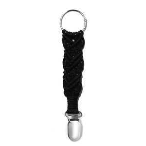 Detail of black macrame hat clip with silver metal ring and clasp on white background