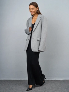 Close-up of minimalist light gray wool blazer paired with black ribbed maxi dress