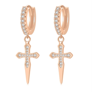 Macro detail of rose gold hoop earrings with iced-out zirconia cross pendants