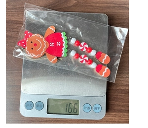 Detailed view of gingerbread girl ornament in red dress on a scale for weight check