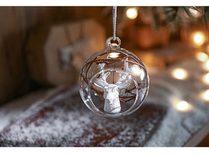 Close-up of glass Christmas ornament featuring a white deer head and festive branch inside