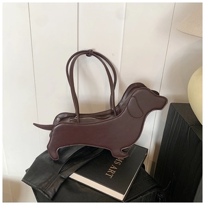 Detailed view of dark brown dachshund shaped PU leather shoulder bag on books