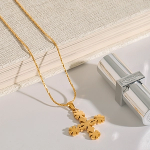 Elegant 18K gold plated stainless steel necklace with a floral cross pendant on a book