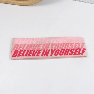 Pink knitted yoga headband featuring white Believe In Yourself text on a clean background