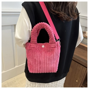 Pink corduroy crossbody bag featuring a soft ribbed texture and white round button detail