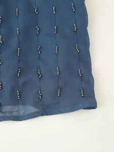Detailed close-up of dark blue chiffon fabric featuring exquisite vertical silver beading