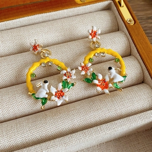 Gros plan sur des boucles d'oreilles vintage en émail avec lapin et fleurs colorées