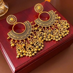 Close-up of vintage golden Jhumka earrings with intricate hollow patterns and small bells