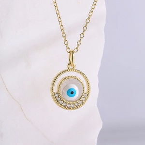 Golden Evil Eye pendant necklace with sparkling zircons on a textured stone background