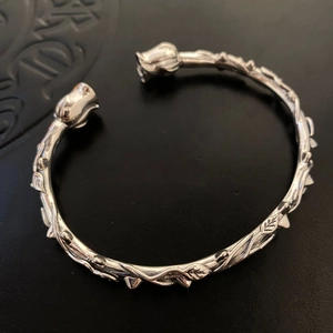 Detailed view of silver thorn rose cuff bracelet on textured black leather background