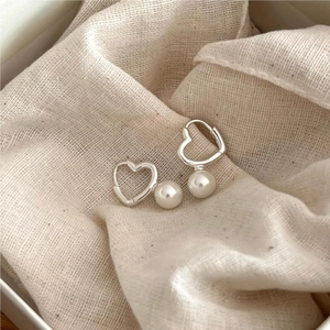 Elegant 925 sterling silver heart earrings with white pearls on soft cream linen texture