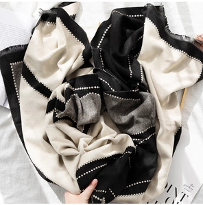 Detail of soft thick scarf featuring black and white geometric patterns and tassel edges