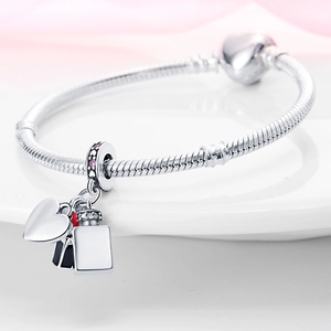 Macro detail of silver charm bracelet with heart, shopping bag and perfume pendants