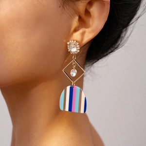 Detail of colorful resin geometric drop earrings with crystals on an elegant female model