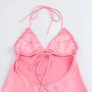 Détail de robe dos nu en satin rose avec ourlet à volants et texture soyeuse