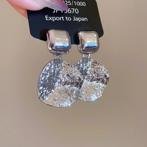 Detail of silver drop earrings with textured square and round metallic pendants