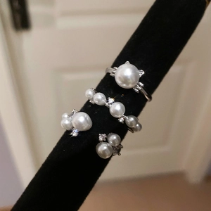 Macro view of four elegant silver rings with pearls displayed on a black velvet stand