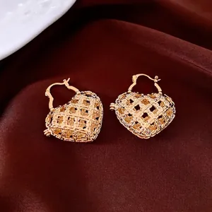 Golden heart-shaped hollow woven earrings on elegant silk background with premium finish
